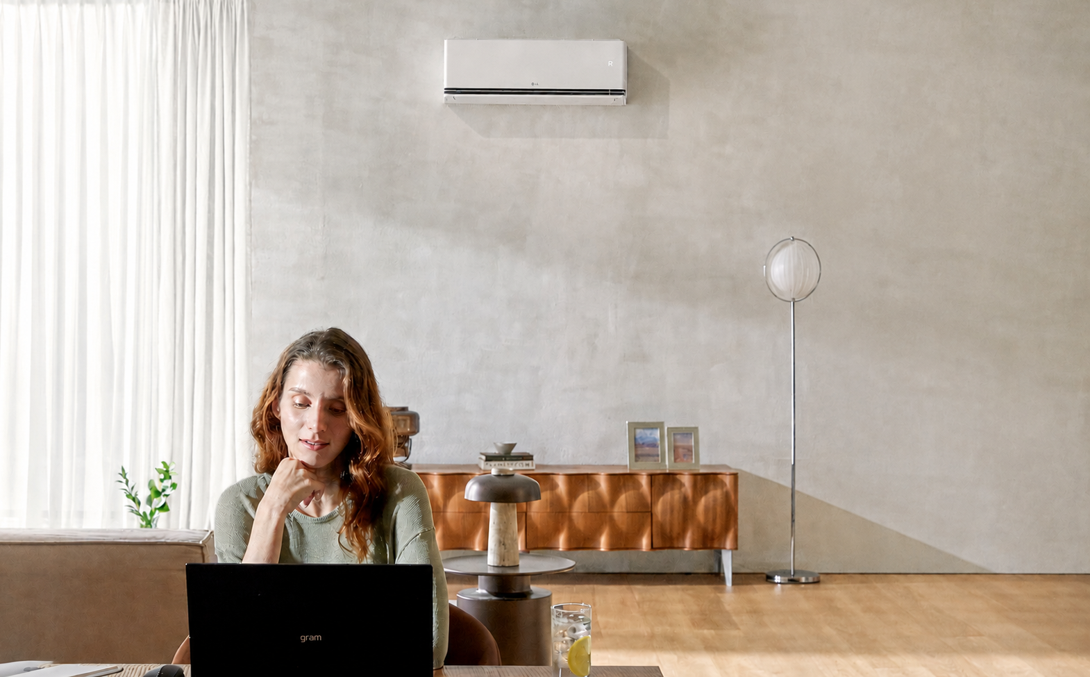 Airco van Maxi Trade luchtventilatie blaast koele lucht in moderne woonkamer terwijl vrouw werkt